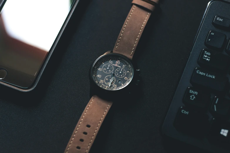 a black watch sitting next to a brown watch