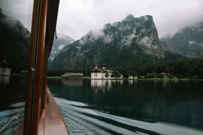 mountains rise above the water and an old building sits on a shore