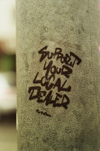 graffiti written on a concrete pillar near some trees