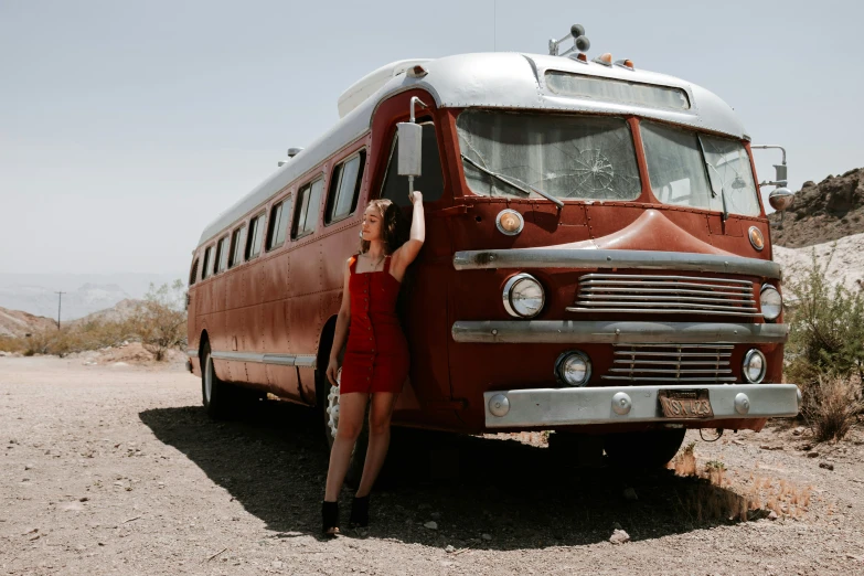 a woman standing next to a brown and white bus