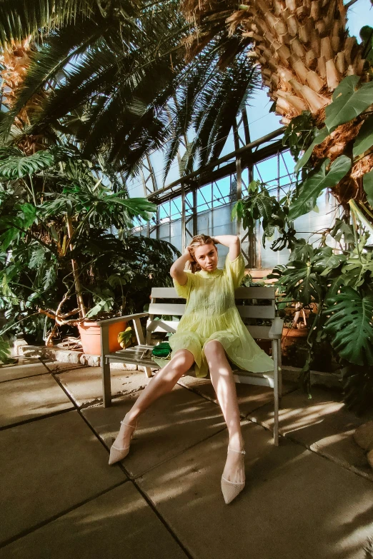 a woman posing for a picture sitting on a bench in the sun