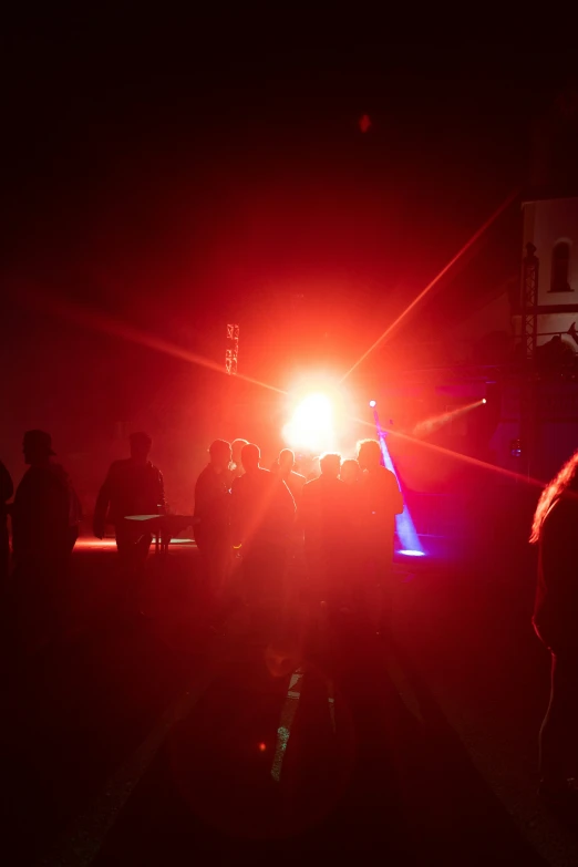 people stand in the dark as the police car lights up