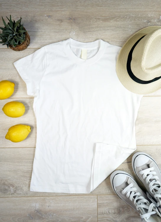 a white tee shirt and yellow lemons on top of a wooden floor