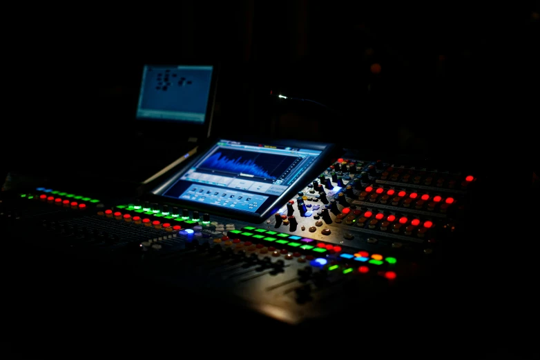 a mixing board and laptop computer in the dark