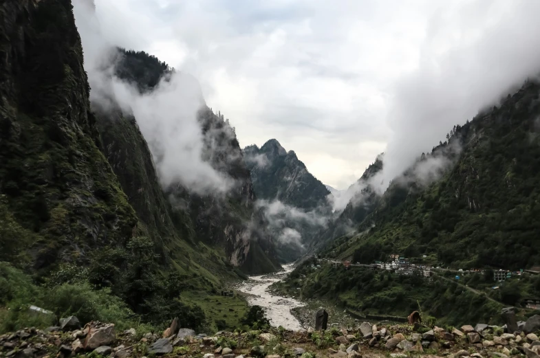 a river surrounded by green mountains next to lush greenery