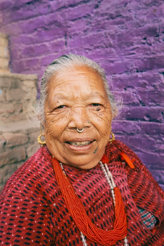 an older woman standing in front of a purple wall