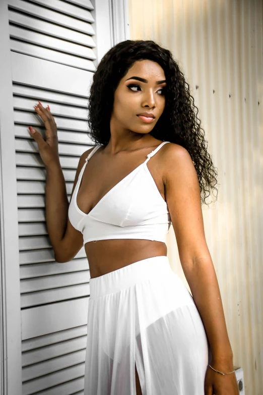 a  young woman standing next to a white wall