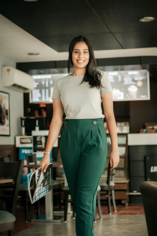 a woman with an open smile and black hair is walking through a restaurant