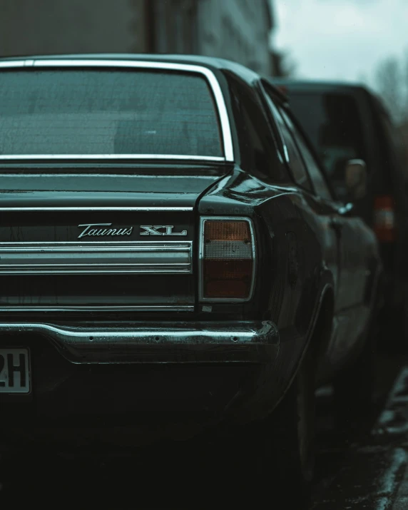 an old black station wagon parked on the side of a street