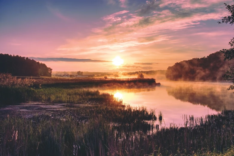 the sunset is reflecting off of a calm lake