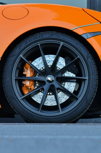an orange sports car with some rims and tires