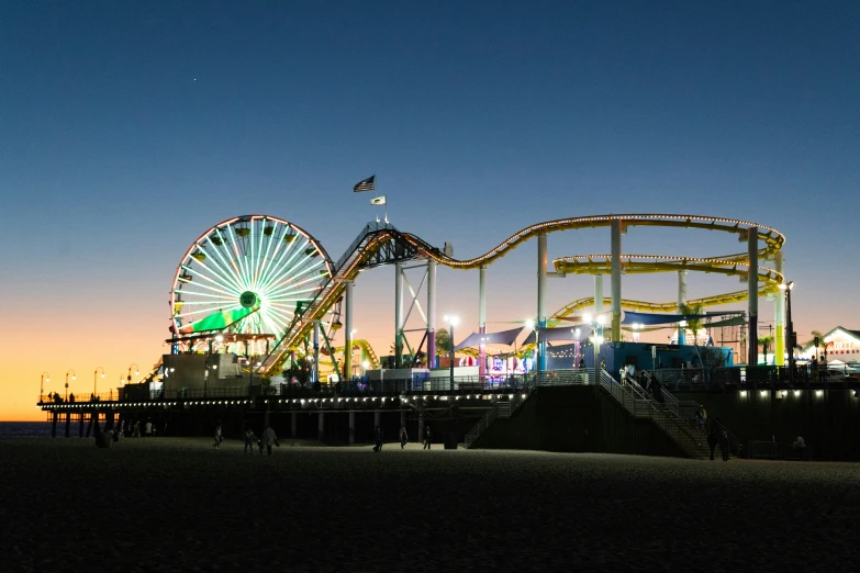 a roller coaster next to the ocean at dusk