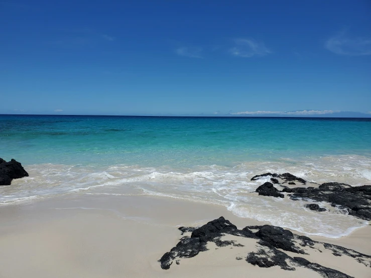 there is a large rock sitting on a sandy beach