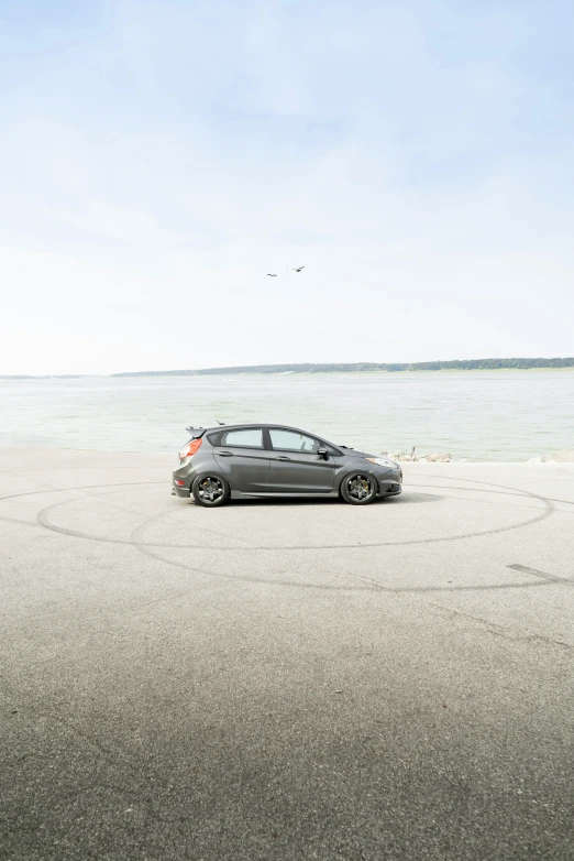 the silver car is sitting in the middle of the sandy beach