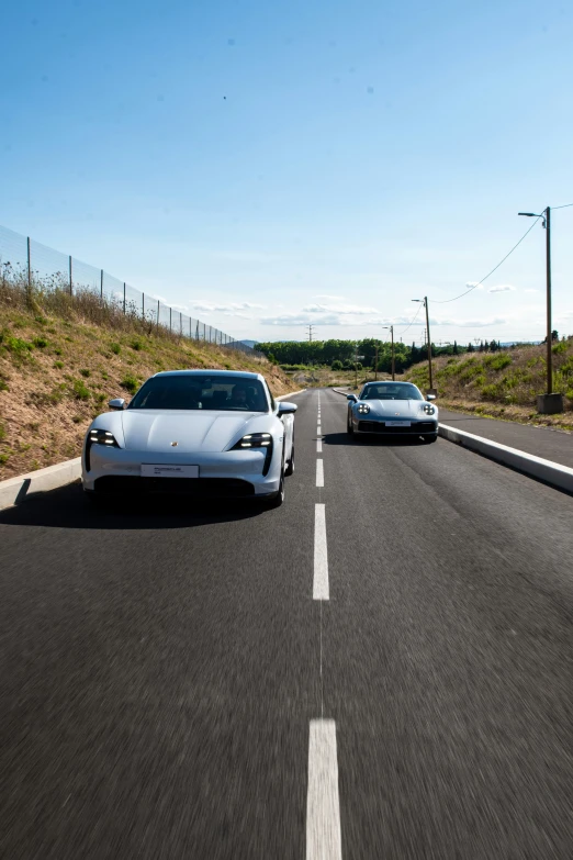 two porsche sports cars driving on a street