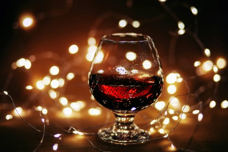 an image of glass of red wine with a string of lights