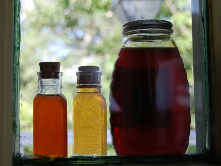 jars filled with liquid sitting on a window sill