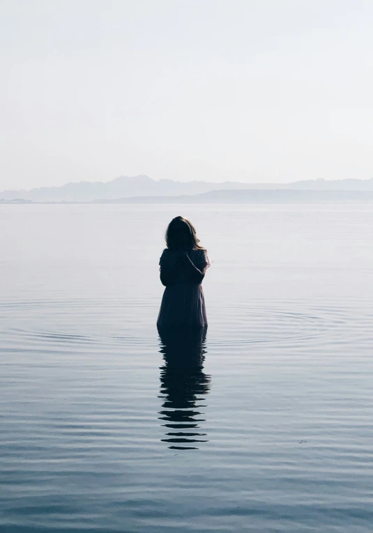 a woman is standing in the water facing away from her head