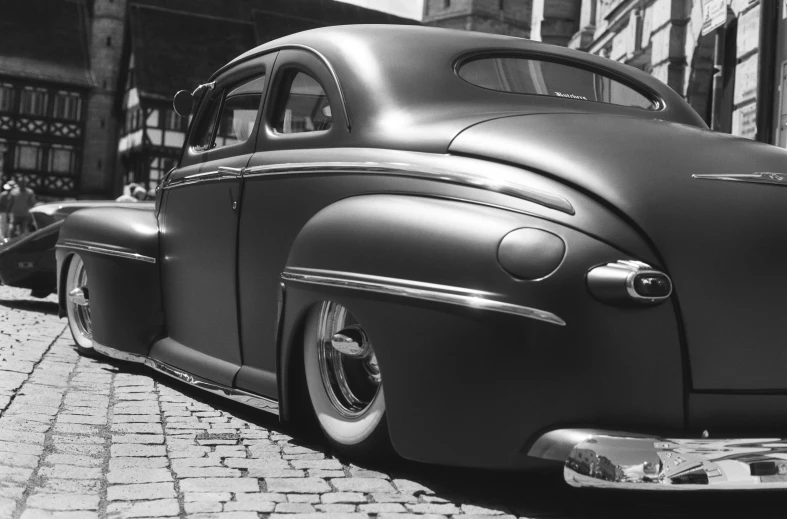 an old black car parked on the side of a street