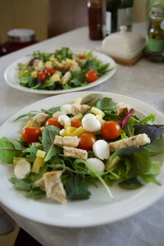 two white plates filled with salad and meat