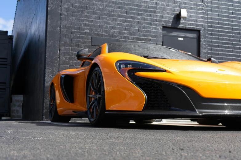 a very nice orange sports car parked in front of a brick building