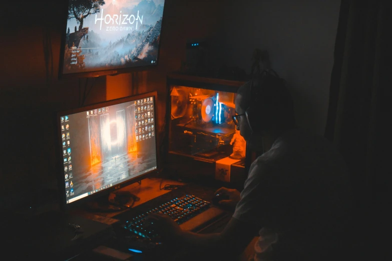 a person in a dark room, with two monitors and two keyboards