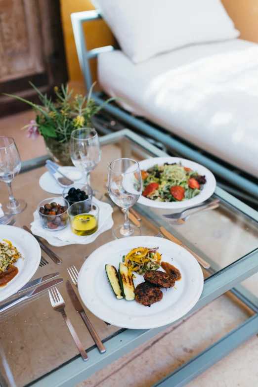 table with three plates of food that include meat, salad and vegetables