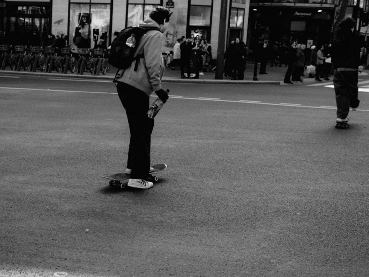 two skateboarders with helmets and backpacks on a street