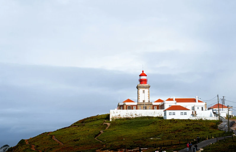 a lighthouse on a hill with some clouds