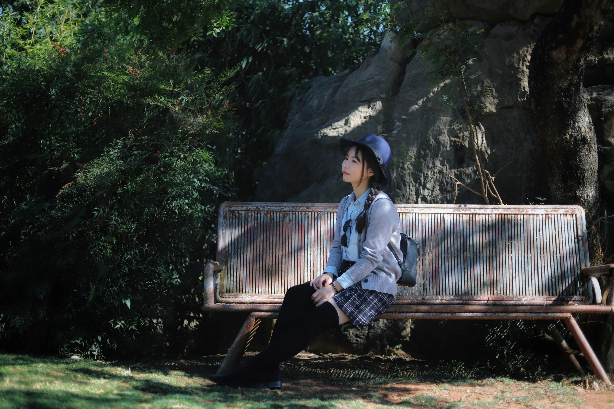 a woman wearing a white hat is sitting on a wooden bench