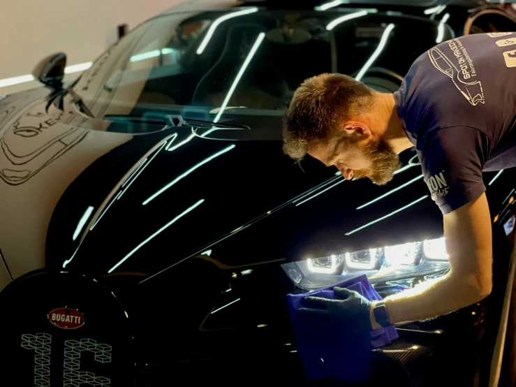 a man is examining the hood of a sports car