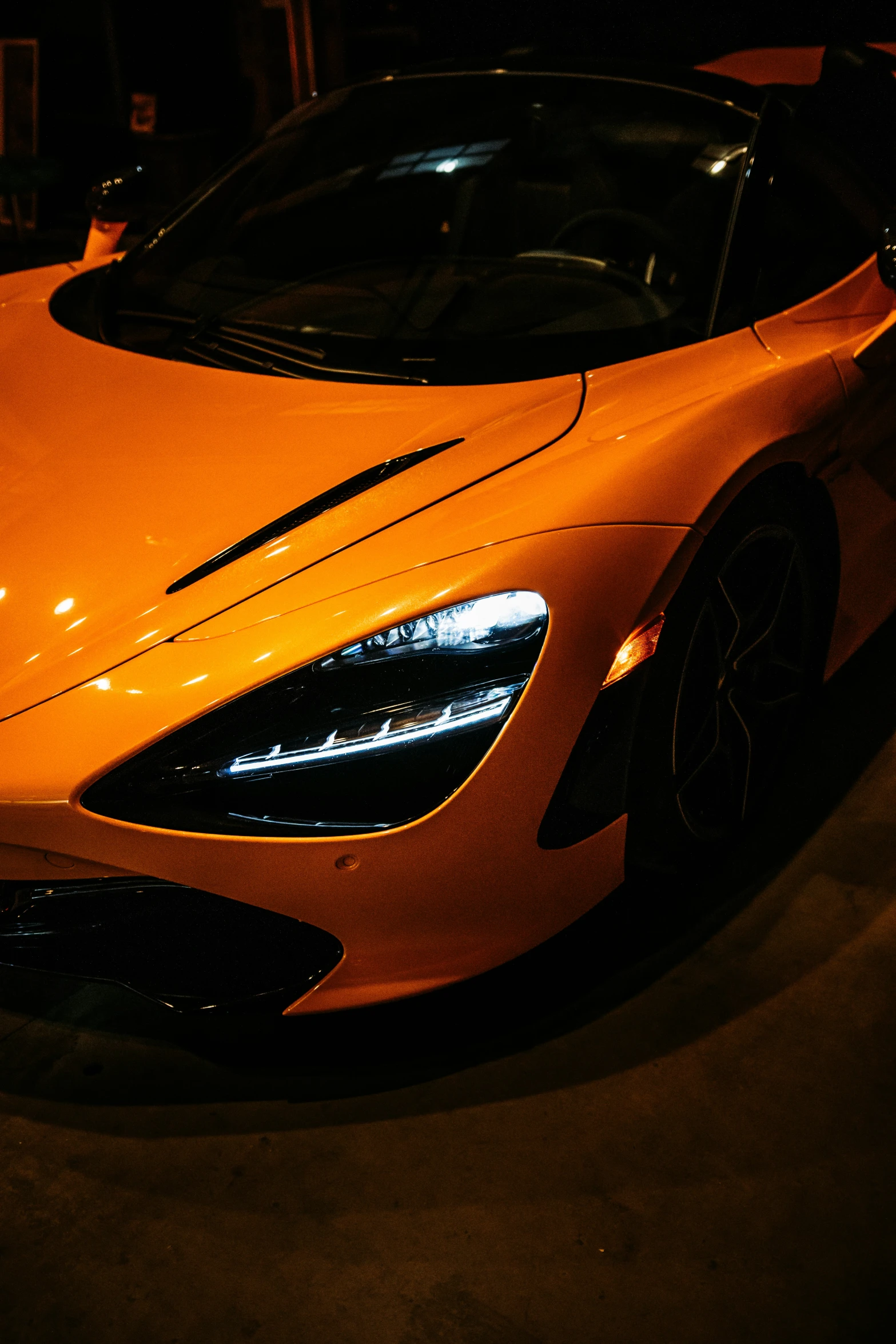 the orange sports car is parked at night