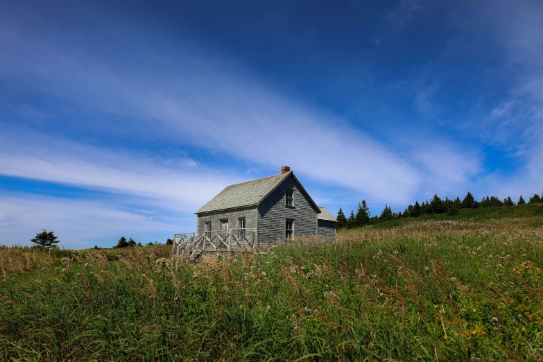 a barn on a hill that looks like it is in the middle of a field