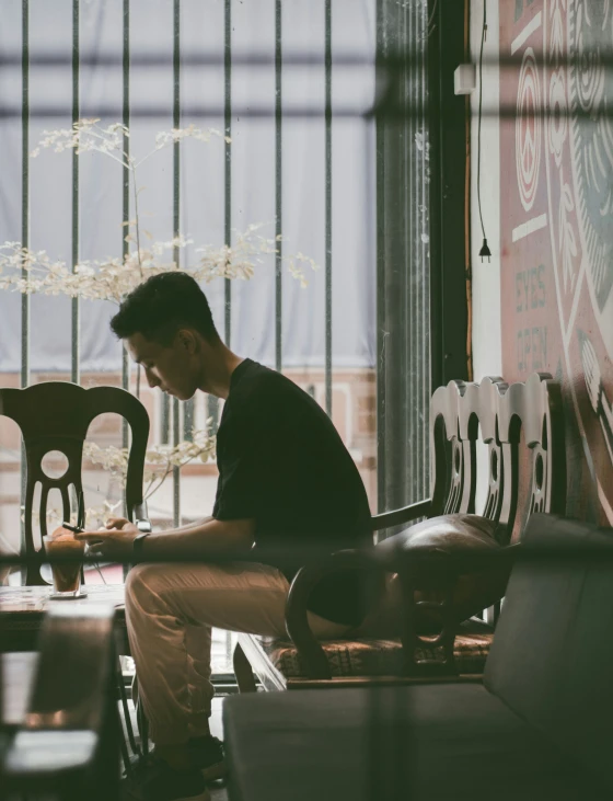 the man is sitting down writing on his cell phone