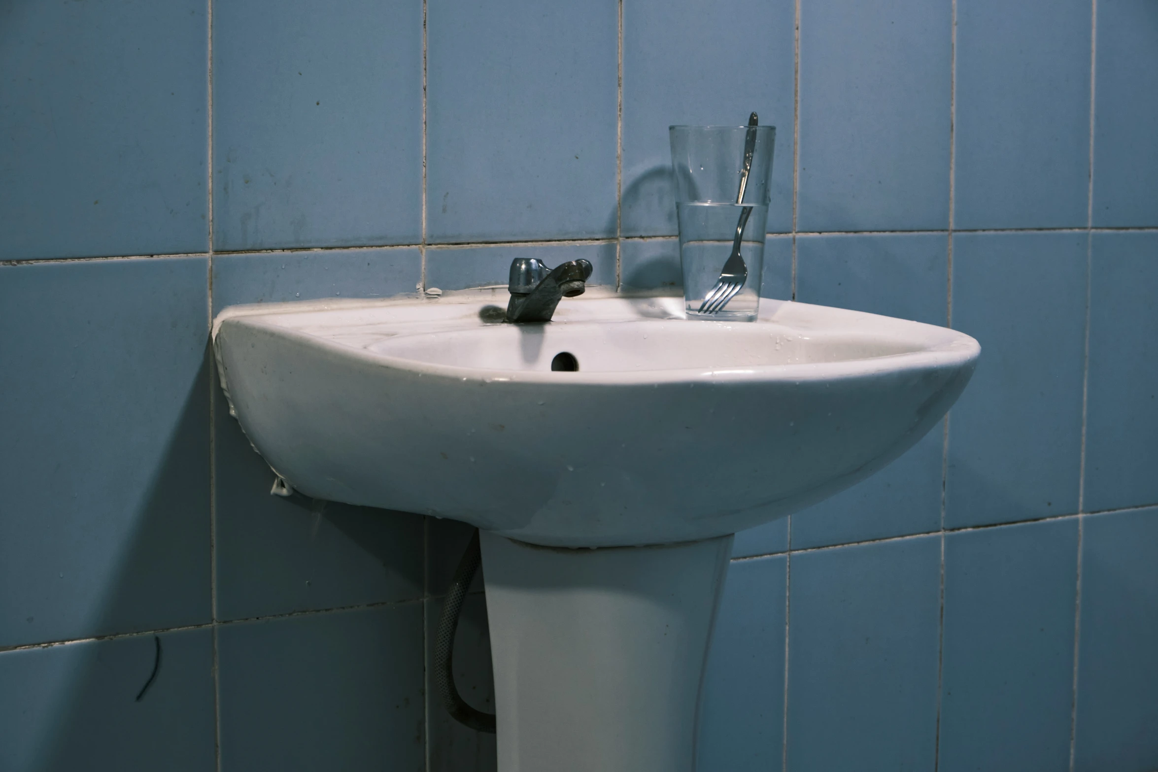 this bathroom features blue tiles and an old fashioned sink