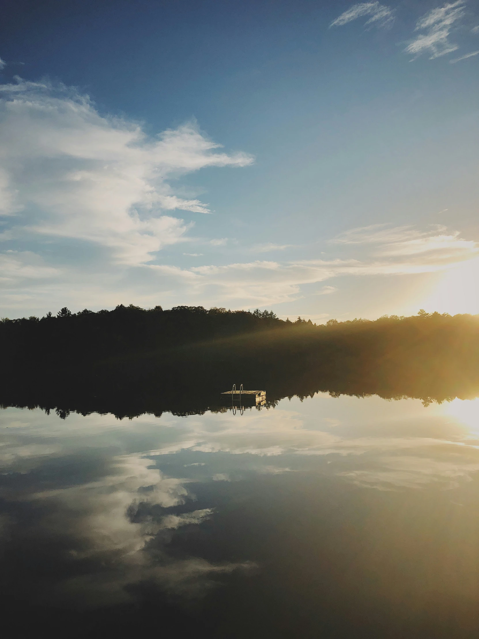 a lake with trees and a boat in it at sunset