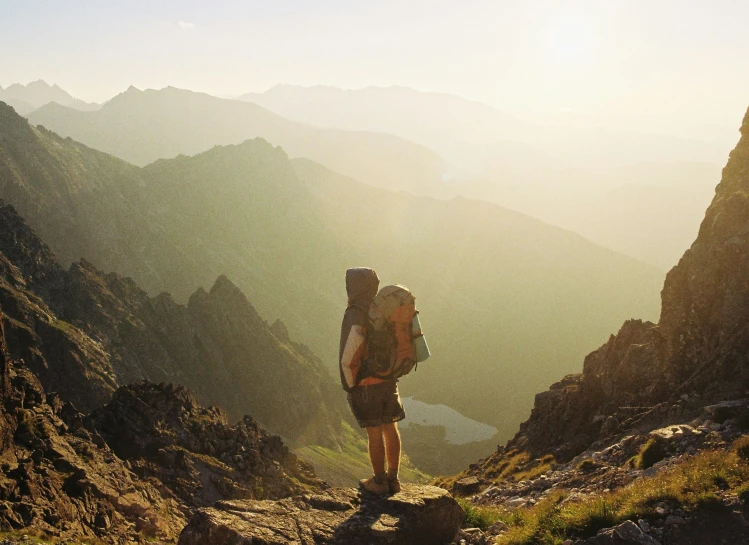 someone with backpack standing on top of mountain side