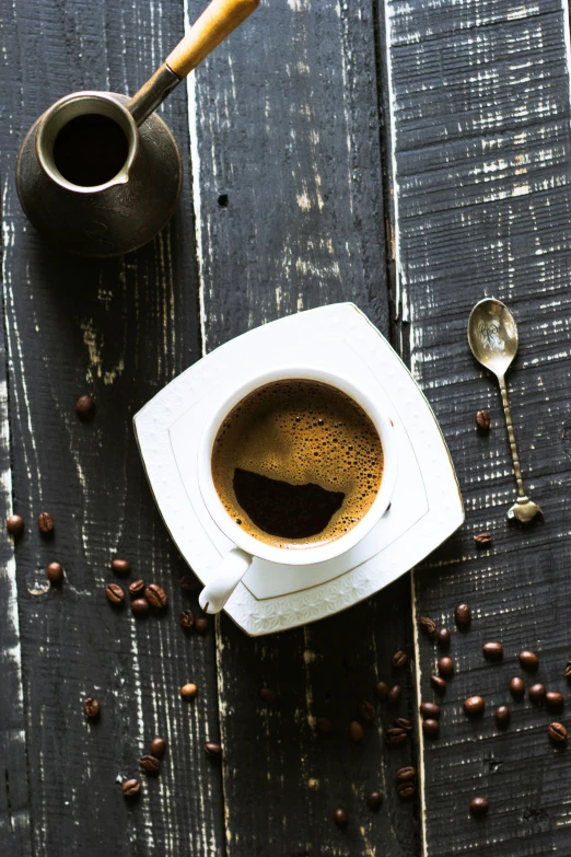 a white plate topped with a cup of coffee next to a coffee pot