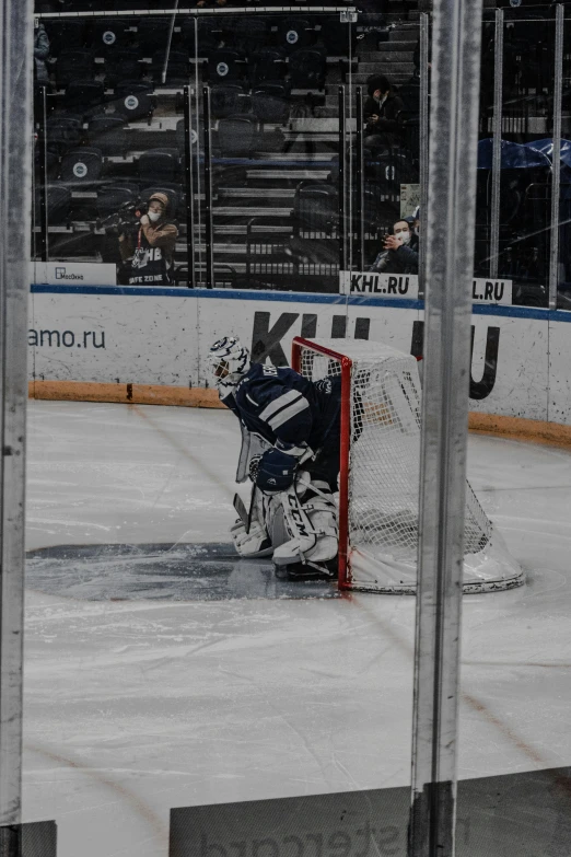 a goaltender sits on the ice near an net