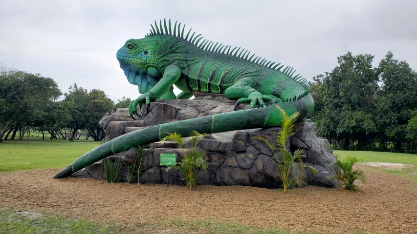 a green statue is near some rocks in a park