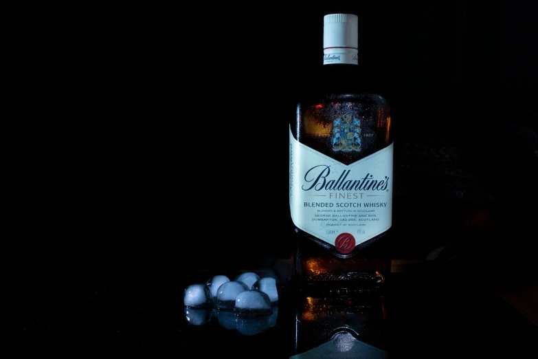 a bottle of whisky with ice balls on a black table