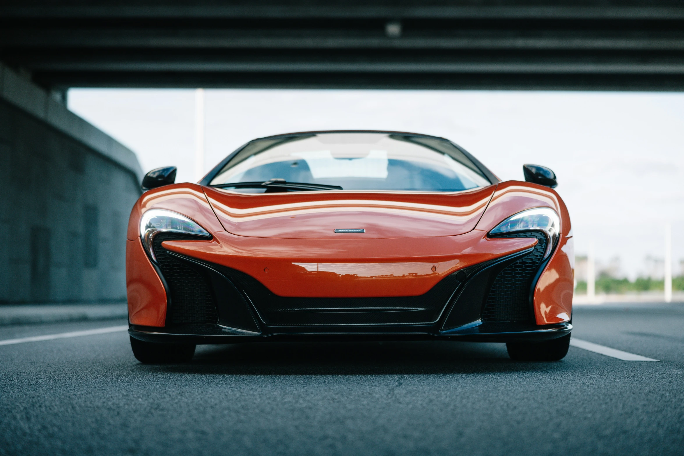 an orange sports car parked in front of a tunnel