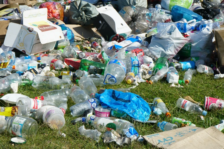 a bunch of garbage laying in the grass with lots of plastic bottles on it