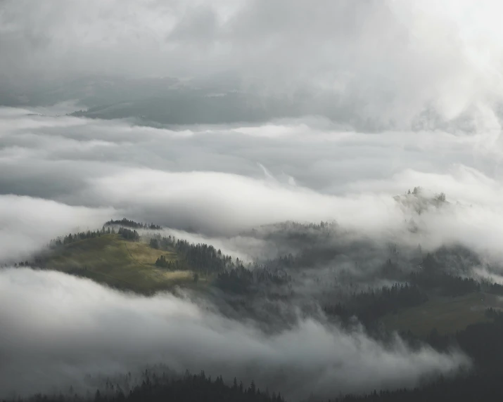 the hills are covered in clouds, trees and hills