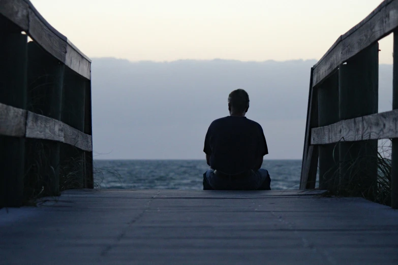 a man sitting down in front of the ocean