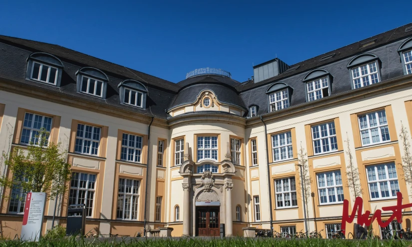 a big building has some grass and flowers on the front