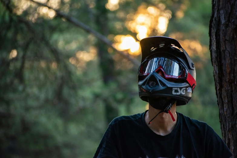 a man wearing a helmet looks out from the woods