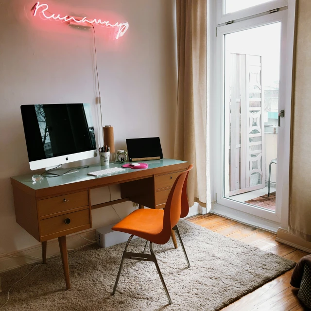 a computer desk sitting underneath a neon sign