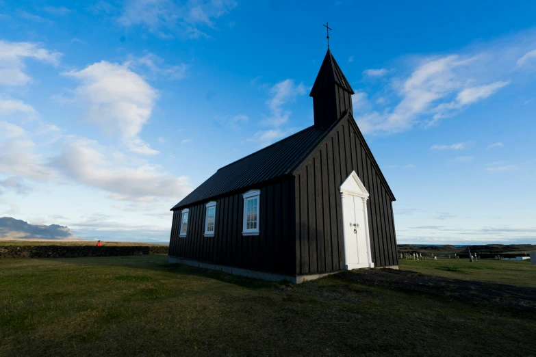 an old church with a steeple is sitting in the grass