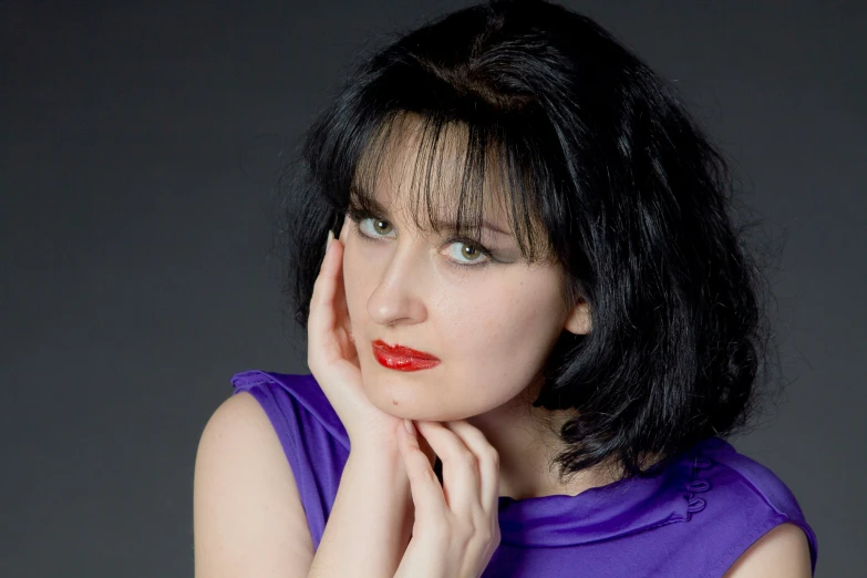 a beautiful lady with dark hair in purple shirt posing for camera